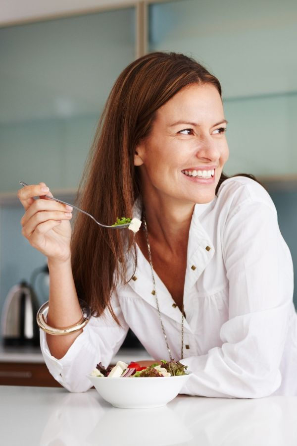 image of a woman in a kitchen enjoying a salad