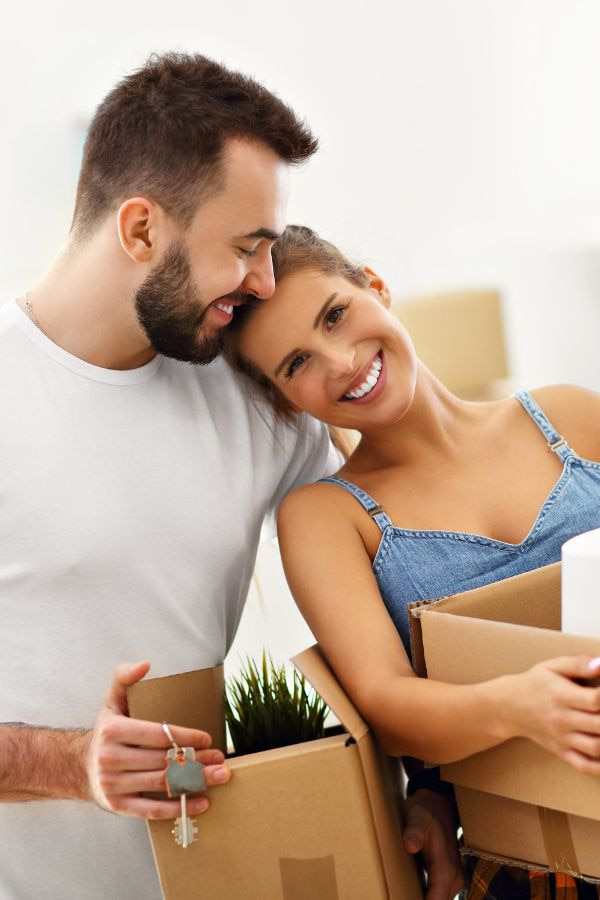 image of a couple smiling and hugging each other while holding boxes