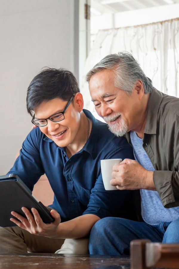 image of a father and son smiling while looking at a tablet